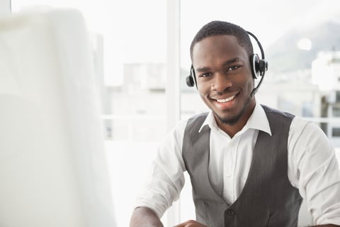 Happy businessman with headset interacting in his office