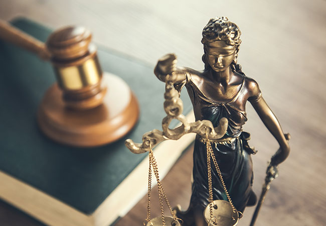 Lady justice with her scales, gavel and law book in the background