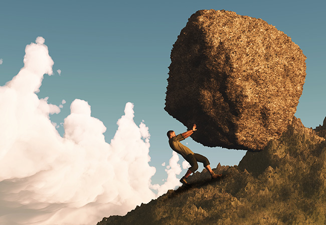 Determined man pushing a boulder up hill
