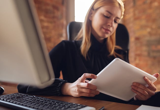 Engaged woman working at her desk with a tablet