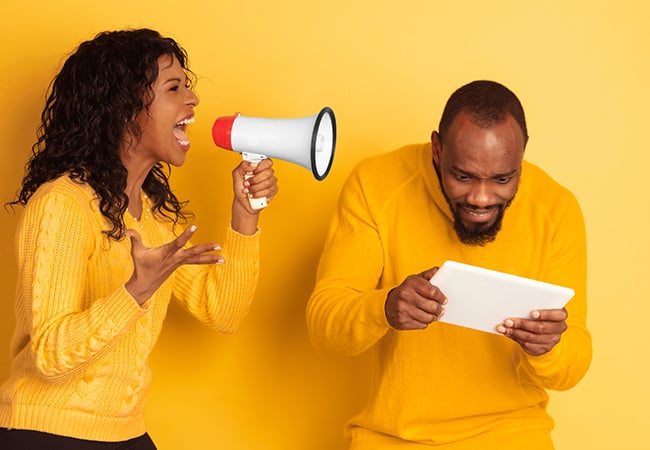 Woman shouting at a man ignoring her while looking at his tablet. 