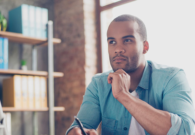 A Man thinking at his desk. 